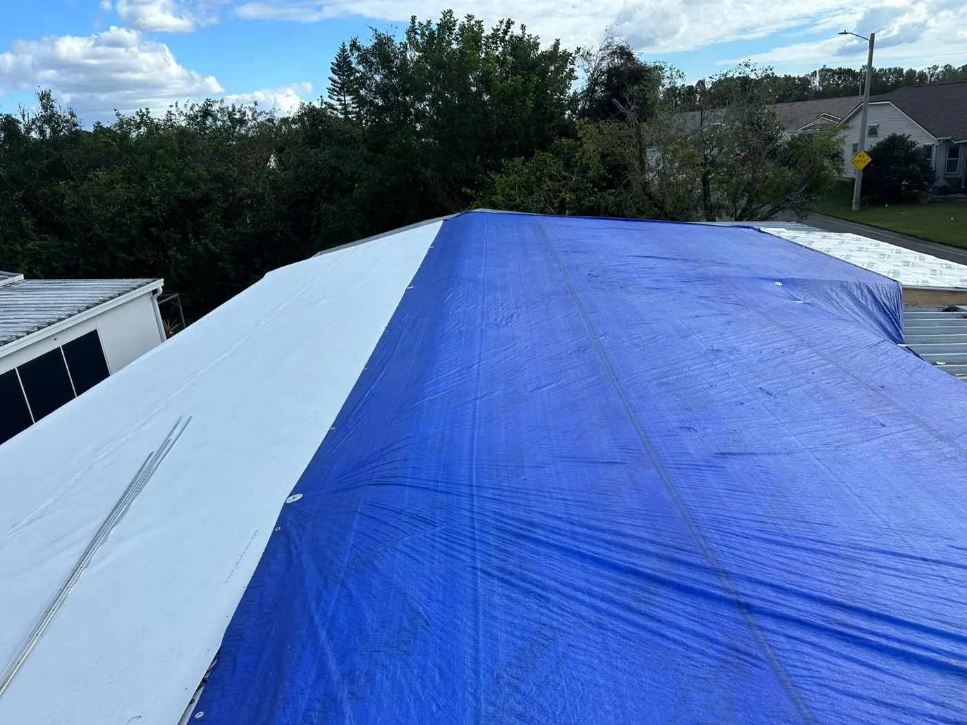 Emergency tarp secured over a low-slope roof after storm damage