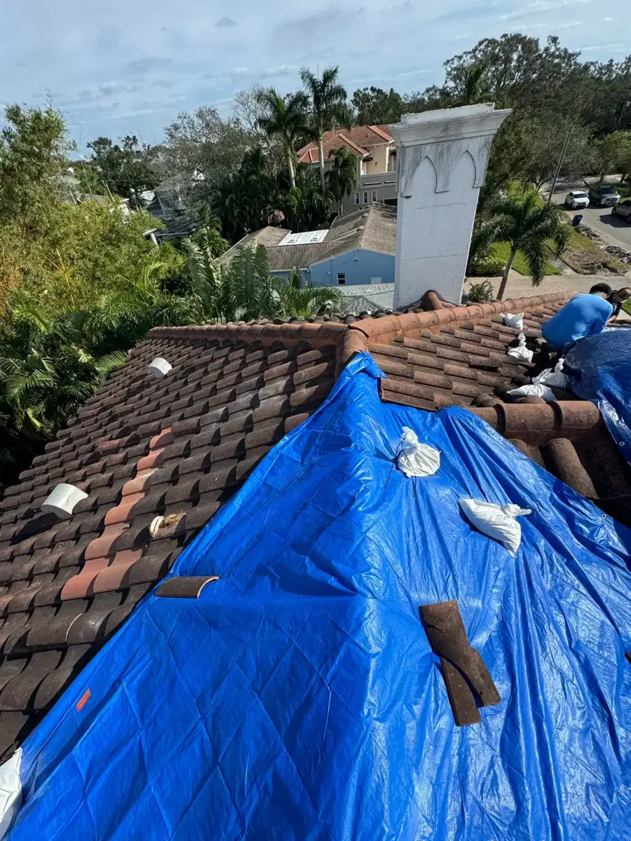 Emergency tarp secured over a damaged tile roof